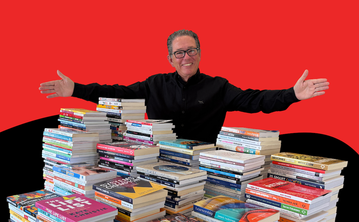 Andrew Griffiths with a table covered in books from authors he has coached