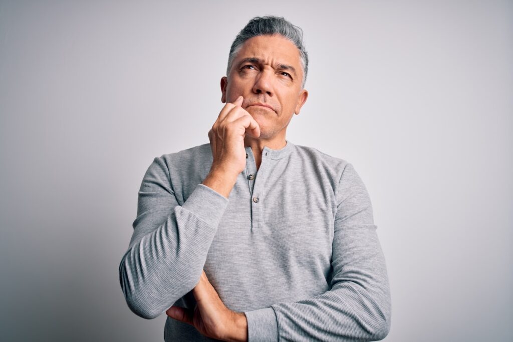 middle aged man look up to sky with questioning expression and hand on face
