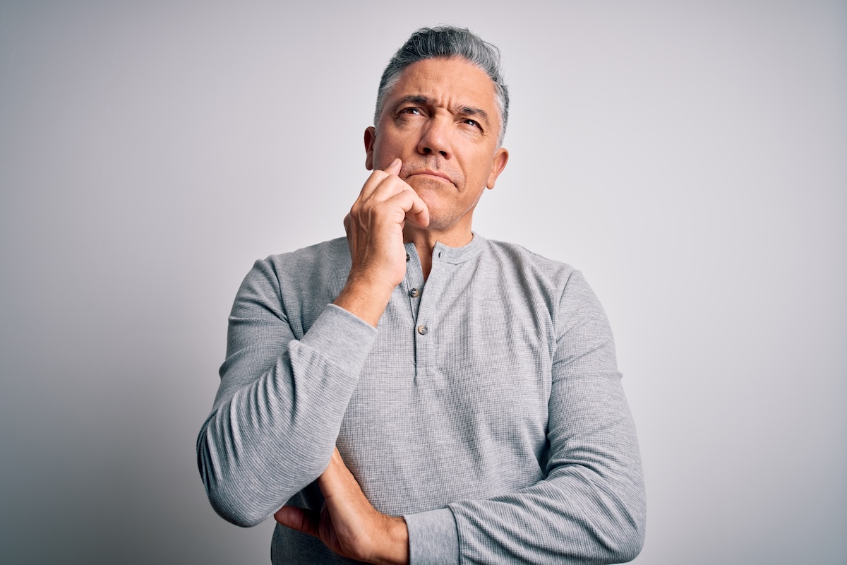 middle aged man look up to sky with questioning expression and hand on face
